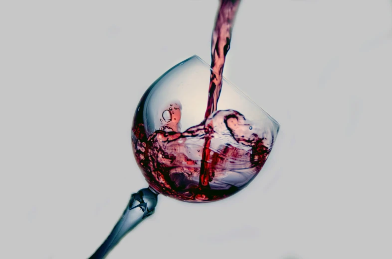 red liquid pouring into wine glass in middle of the day