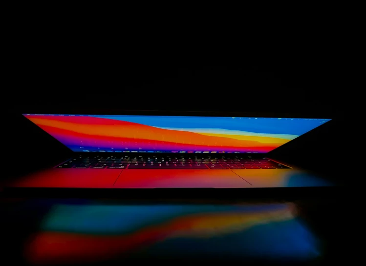 a brightly colored laptop computer sitting on a dark surface