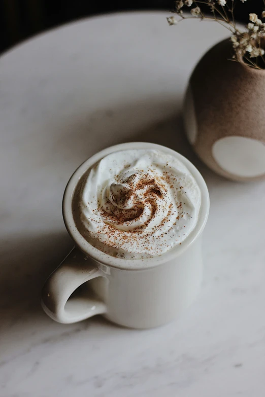 a white cup filled with latte on top of a counter