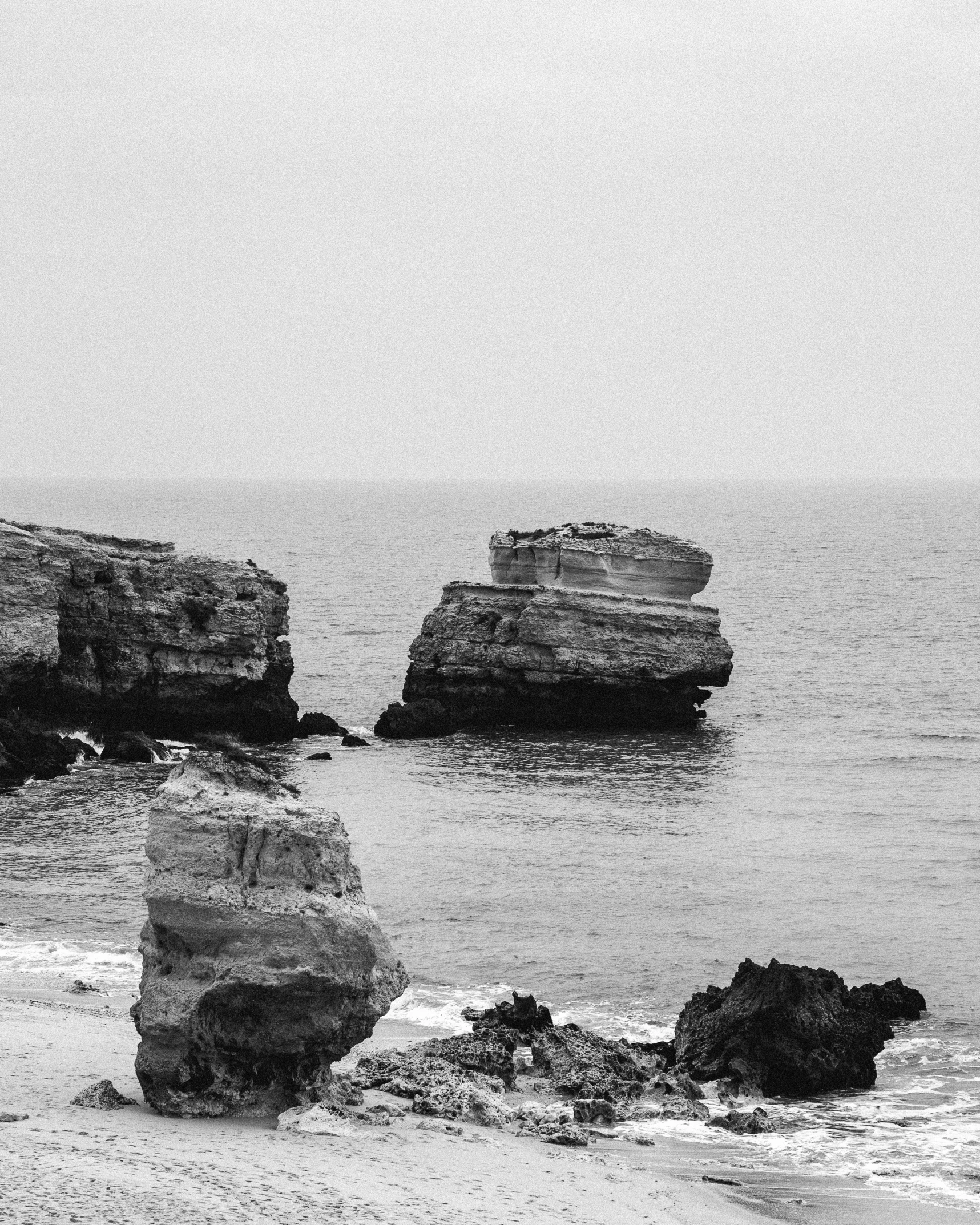 some rocks that are in the sand by the water