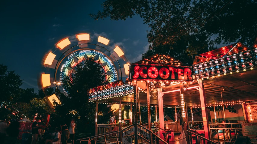 a carousel and rides at night on a dark, wooded city street