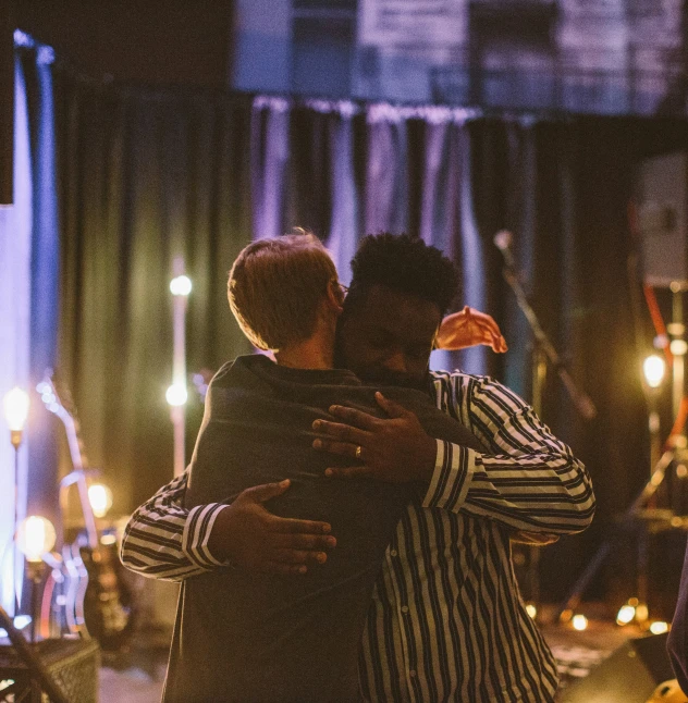 people hugging and a microphone with a large number of lights in the background