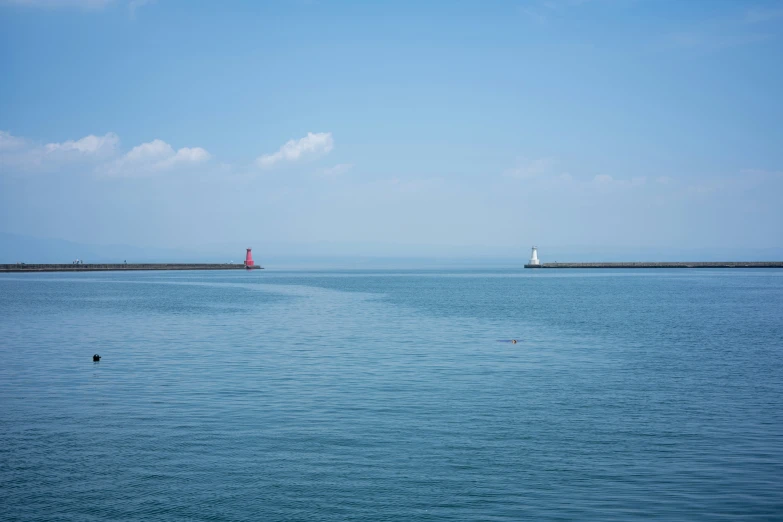 blue water, a light house, and two ships sailing on it