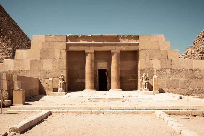 a close up of some statues near two pyramids