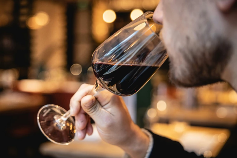 a man holding up a wine glass filled with red liquid