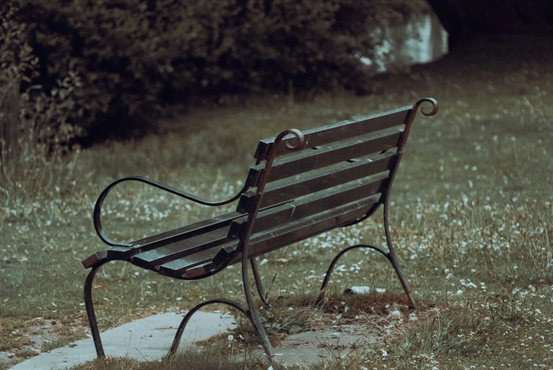 a park bench sits alone in an open field