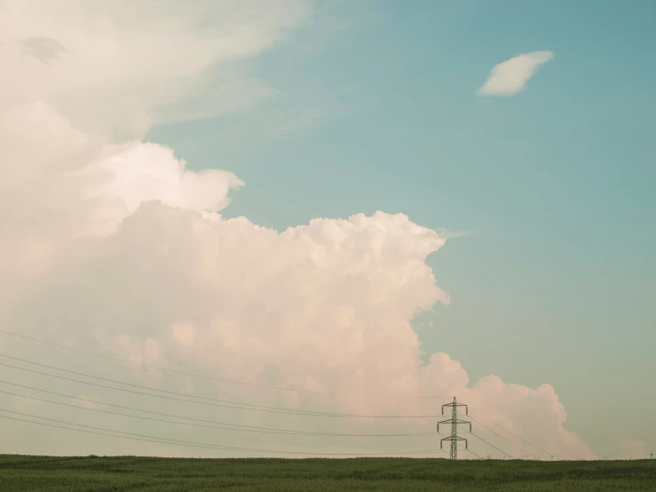 two utility poles sit under a cloud filled sky