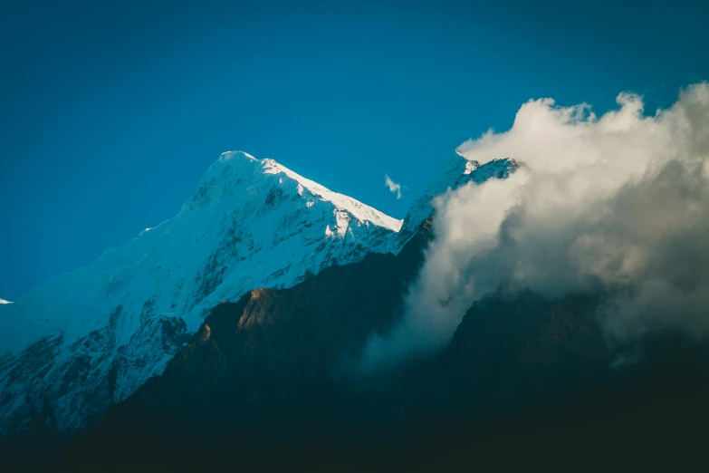 a high up snow covered mountain with white clouds