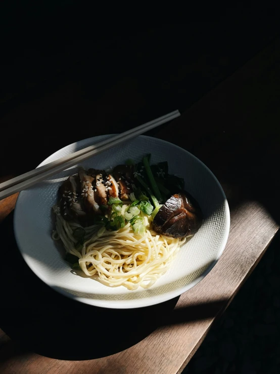 white plate on brown wooden table with shrimp, noodles, and vegetables