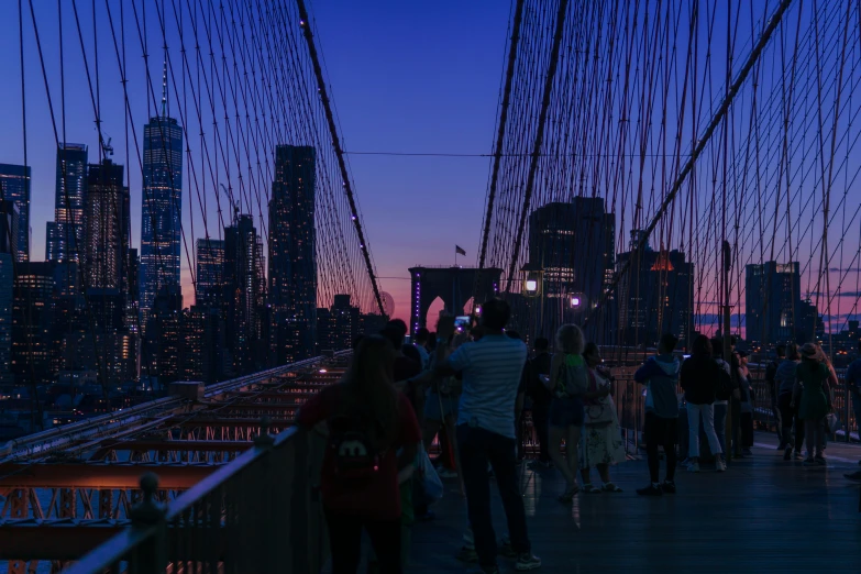 people standing on a bridge as the sun sets