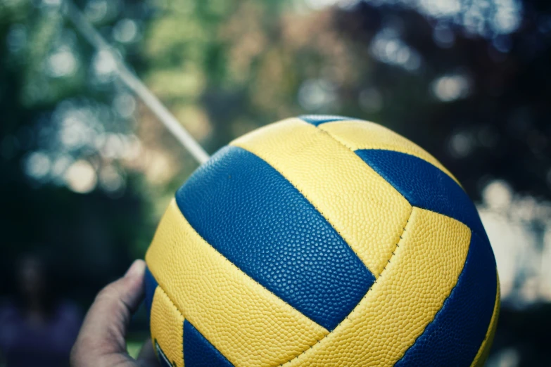 closeup of a yellow and blue leather soccer ball with the background blurred
