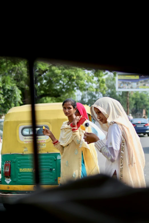 two women are talking as they pass by a bus