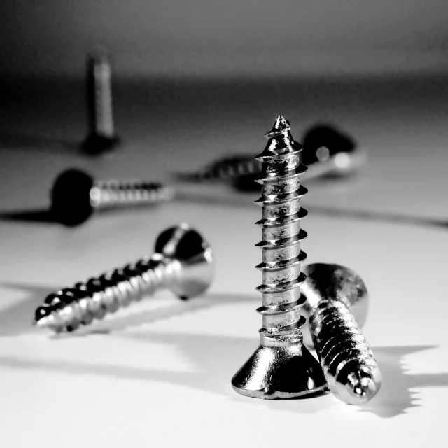 three different screws and a pair of round heads on a table