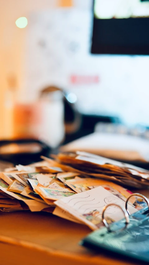 many stacks of paper sitting on a wooden desk