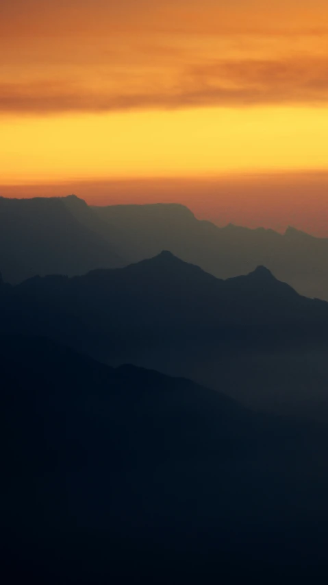 the view from a plane during sunset as it flies over mountains