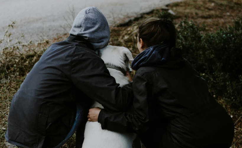 a couple hugging and kissing as they walk their dog outside