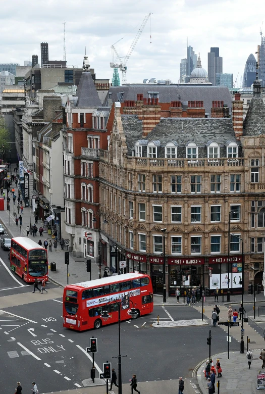 a big city street has red double decker buses