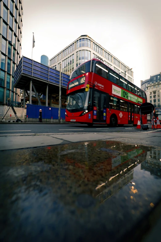 a big double decker bus on a road next to buildings