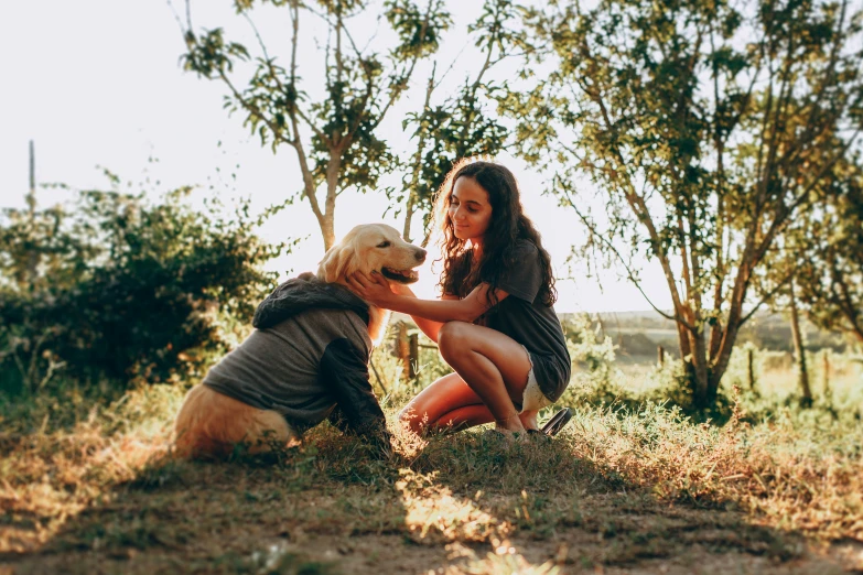 a woman kneeling down with a dog in front of her