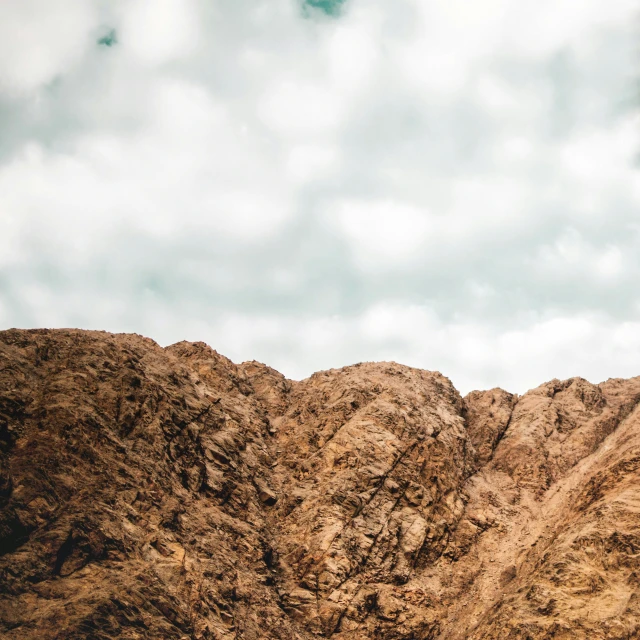 a dirt hill with mountains and a small sky above it