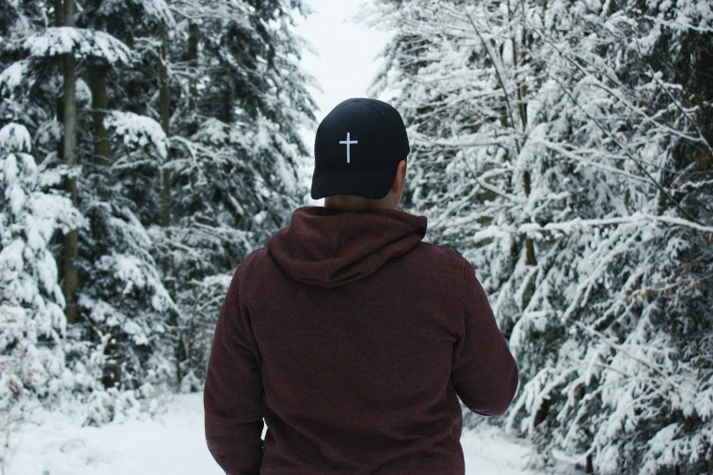 the man wearing a maroon hoodie is standing in the snow