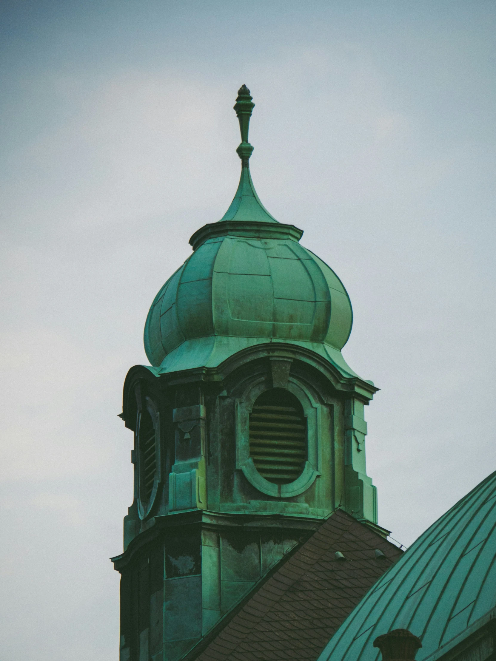 a steeple with a green top with a clock on it