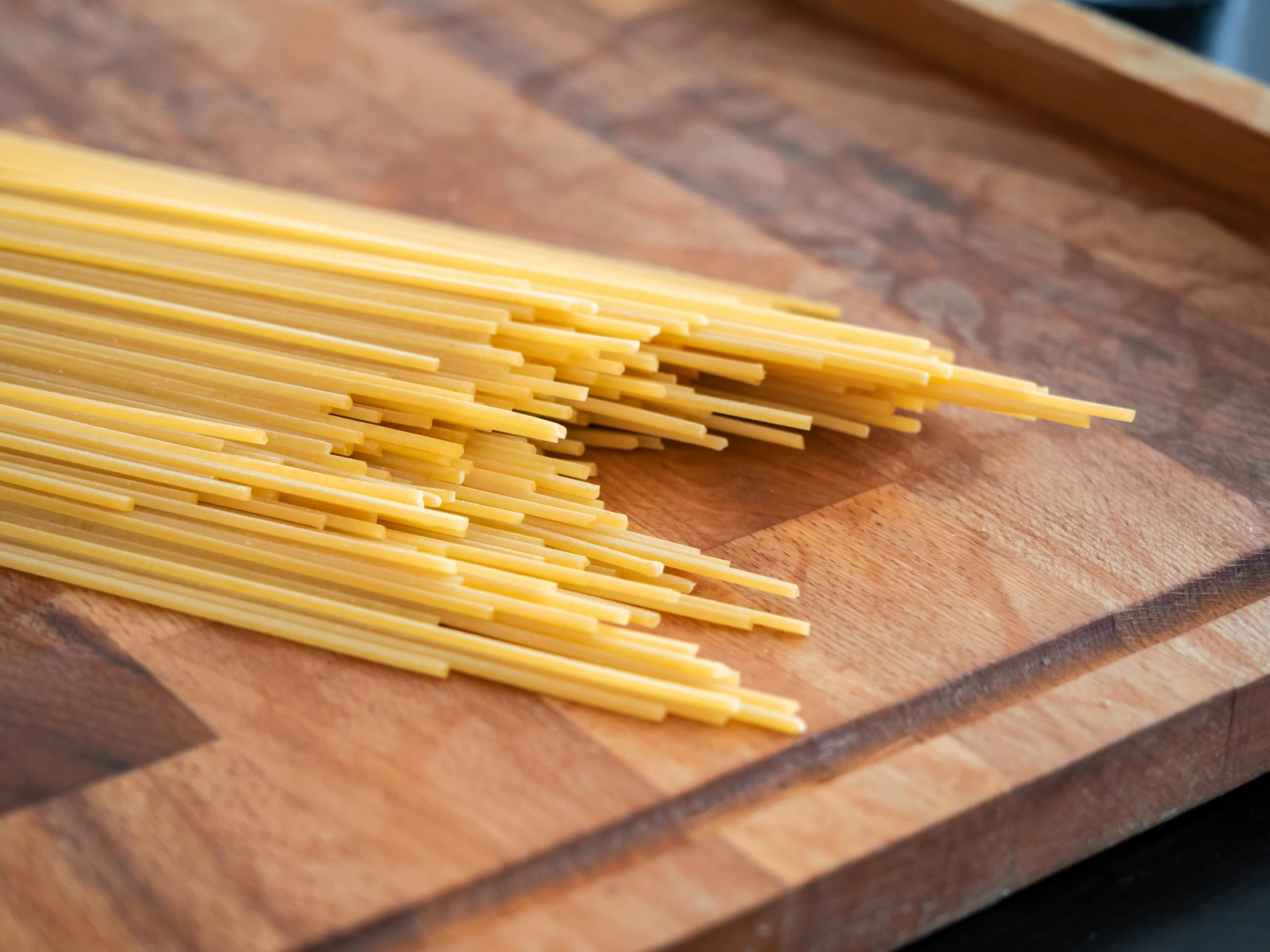 a bunch of uncooked spaghetti sitting on top of a wooden  board