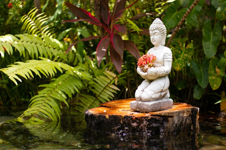 a statue holding a bouquet in a wooded area