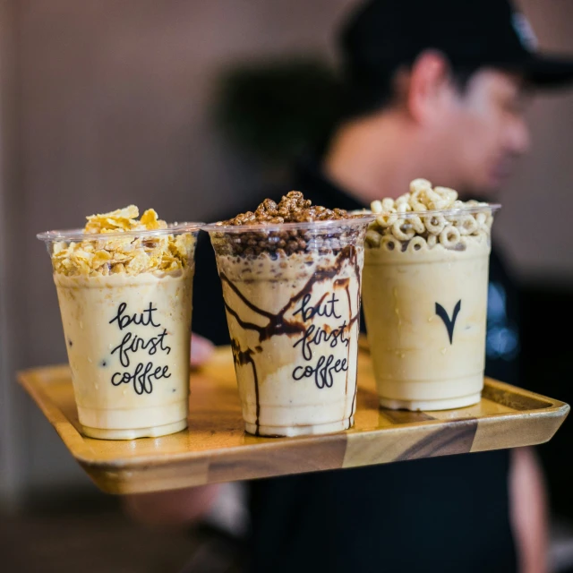 three drinks, each with a different flavor of topping, are sitting on a tray