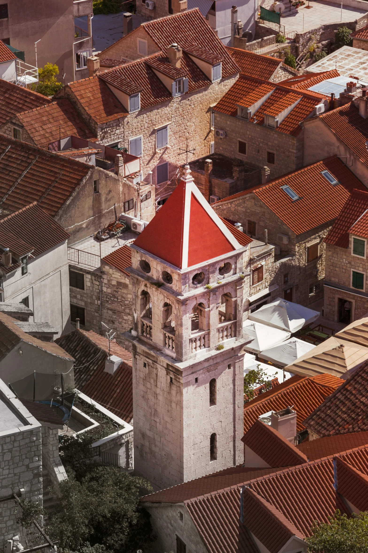 a tall building with a red roof top next to some white buildings