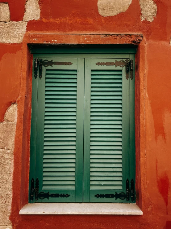 green shutters on an old red wall and window