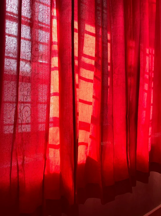 the red curtains glow through a window