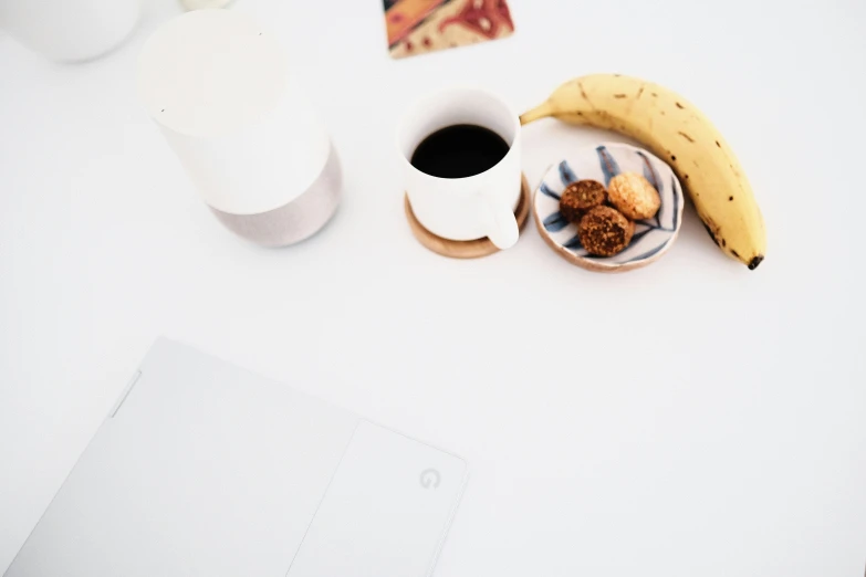 a cup of coffee, banana, nuts and nutshells are laid out