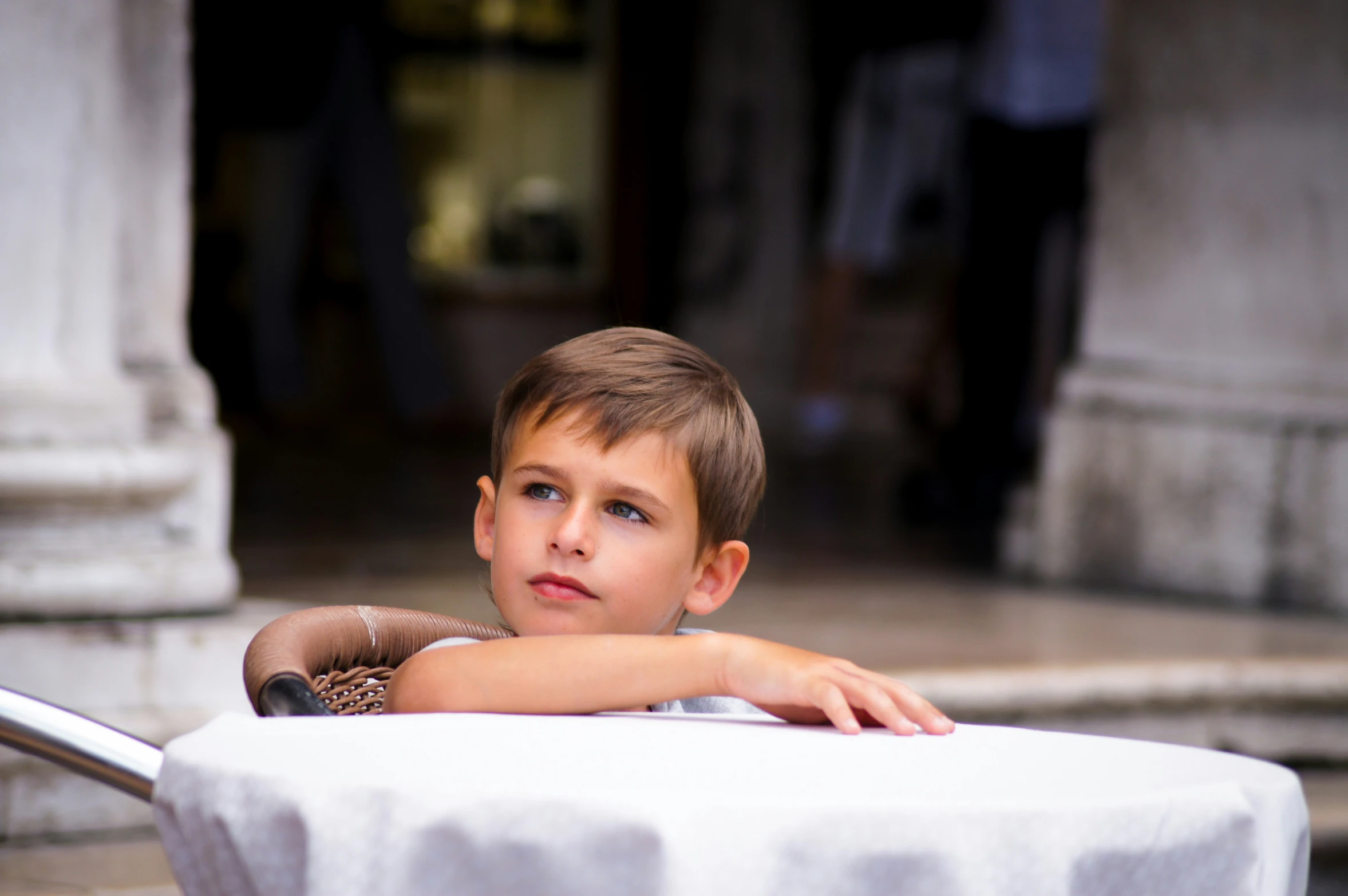 a boy sitting at the back of a bench with his hand on his hips