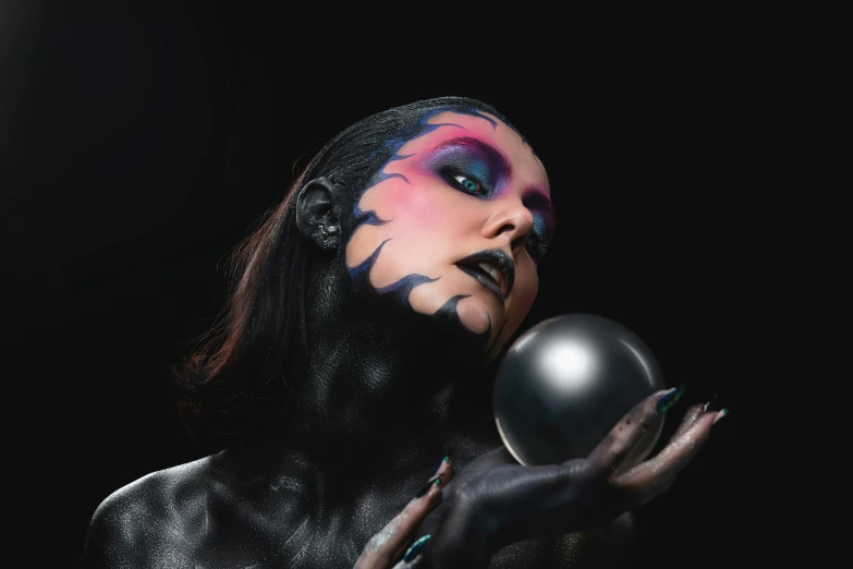 a woman in black holding a silver ball