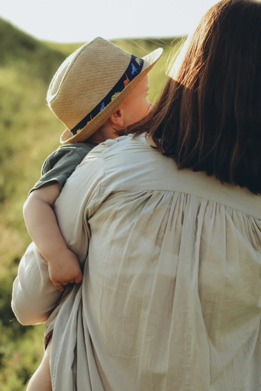 a child in a beige shirt and a hat holding a parent