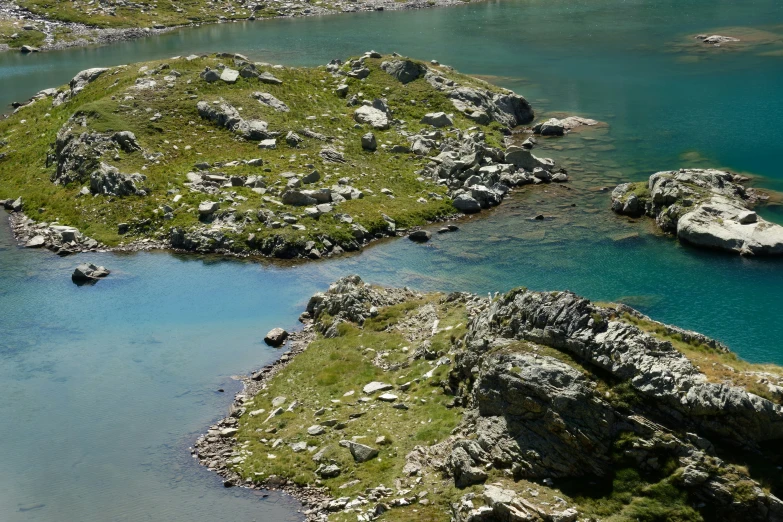 three rocks in the water with grass on top