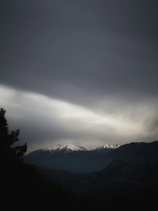 a hill that is filled with trees and dark clouds