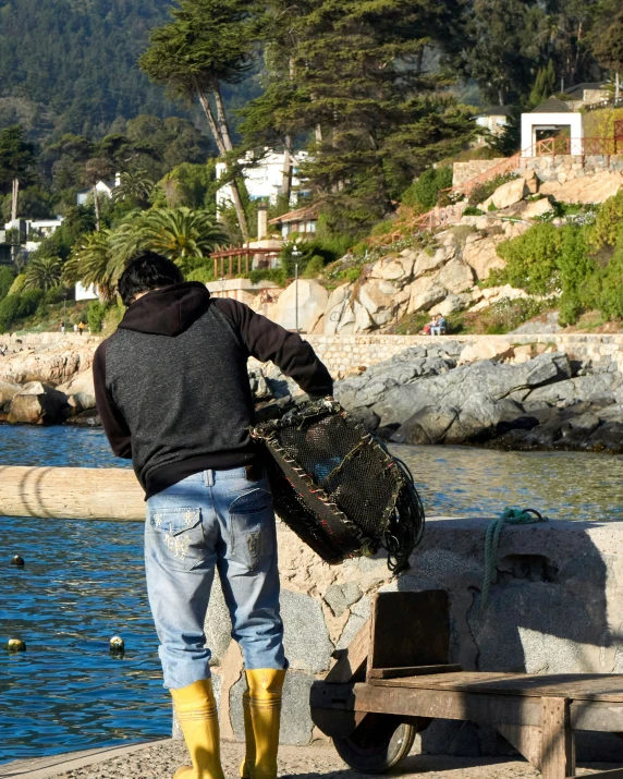 a person standing in front of water holding a basket and a plastic bottle