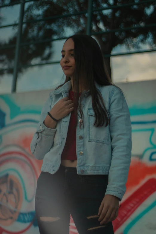 a woman with long hair is standing by a wall