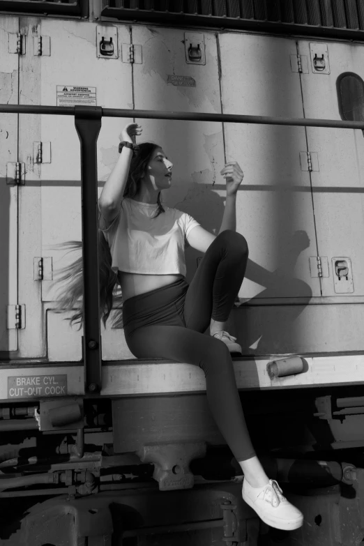 black and white pograph of a woman sitting on the back of a moving truck