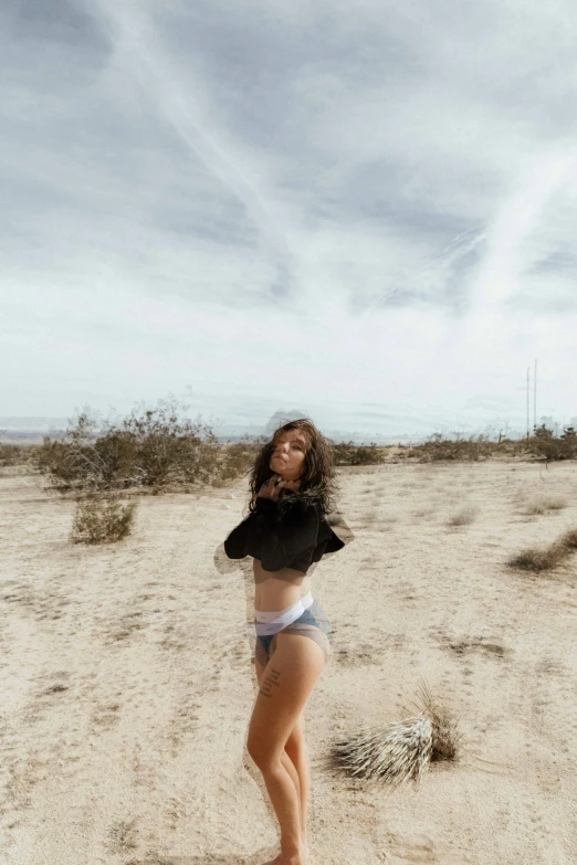 a woman stands in the middle of a sandy desert