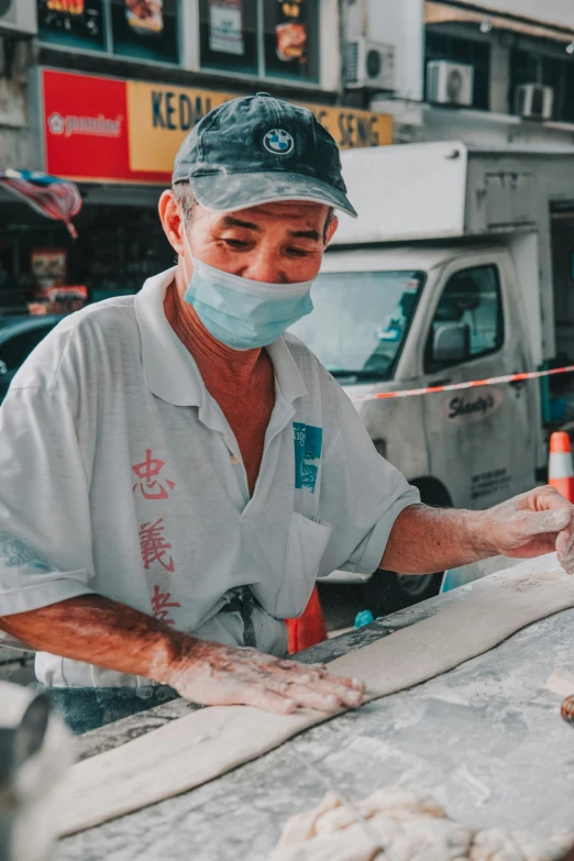 man in a white shirt and a black mask wearing protective clothing working on a large slab