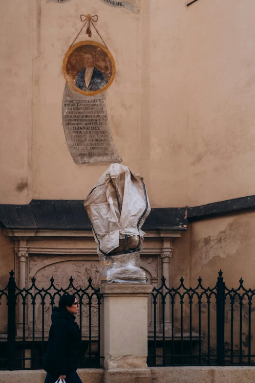 the man is walking past a sculpture on the sidewalk