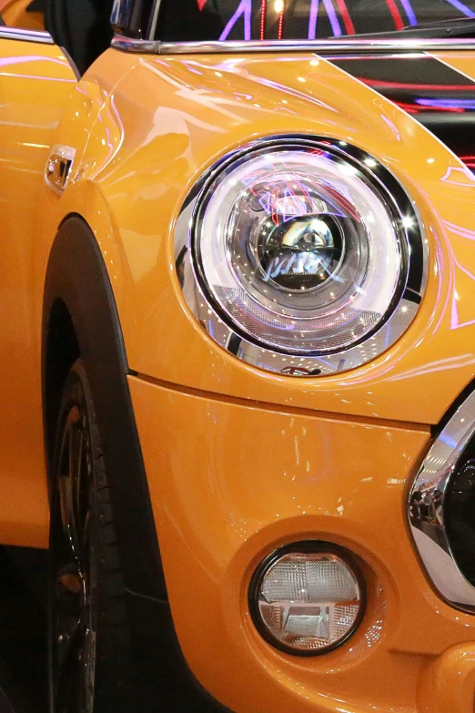 the front end of a yellow mini cooper car with light up