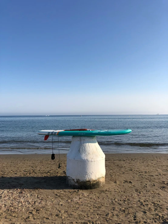 a surfboard rests on top of a rock on a beach