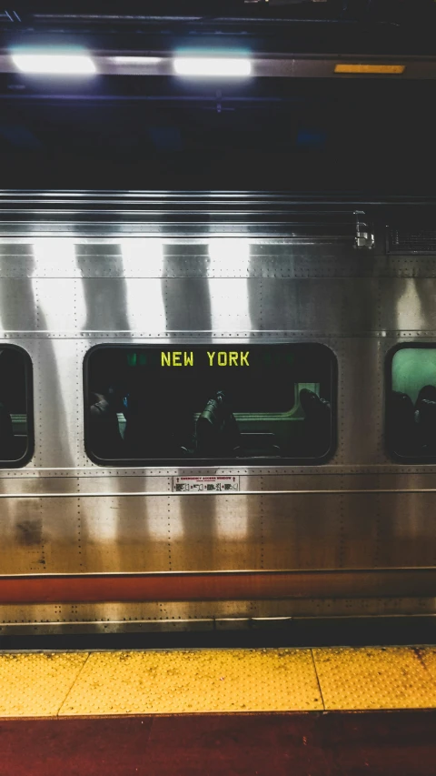 a silver subway train with yellow door and new york written in the door