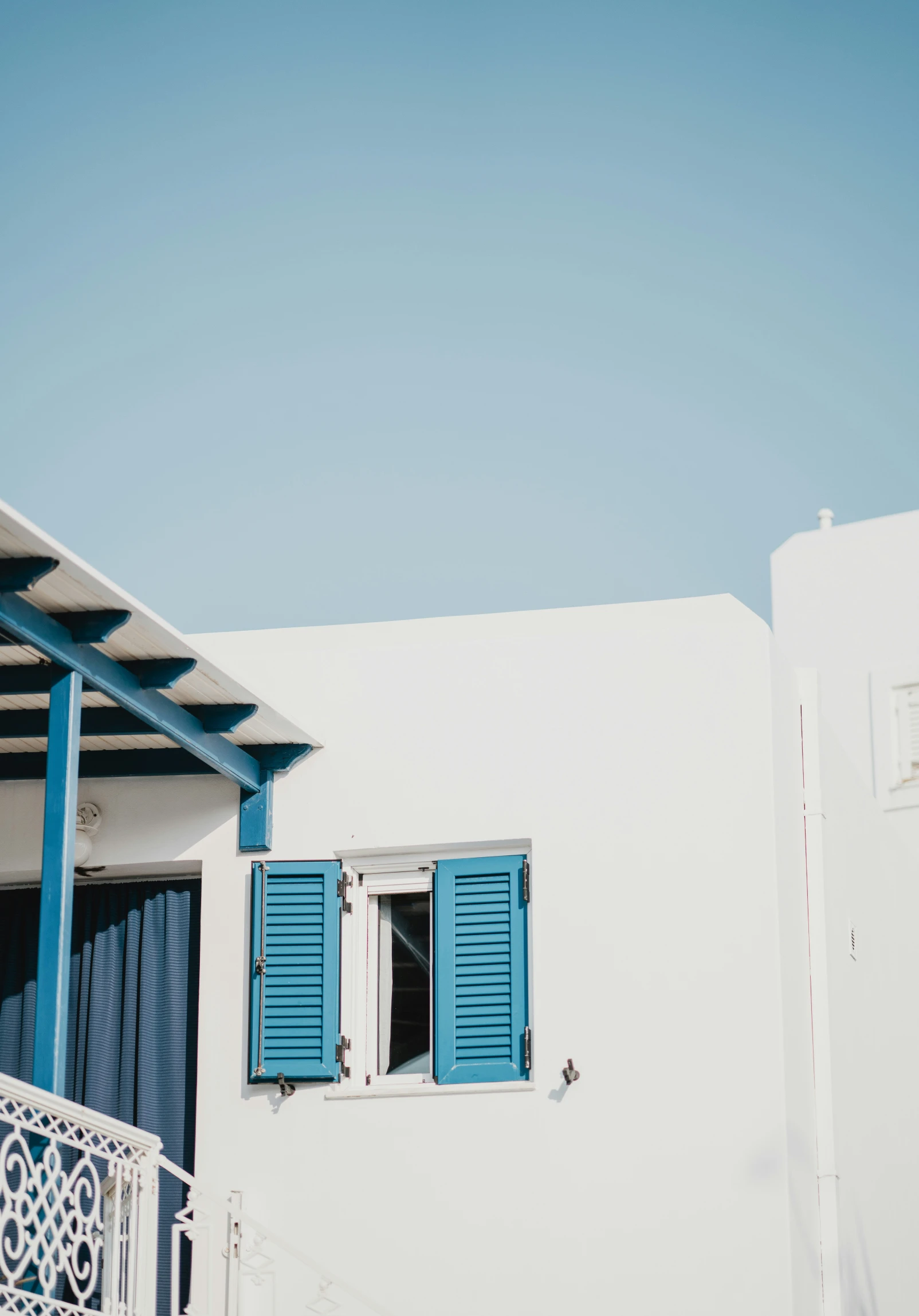 a balcony with blue shutters and a white building