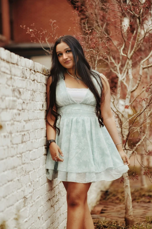 a beautiful young lady leaning against a wall