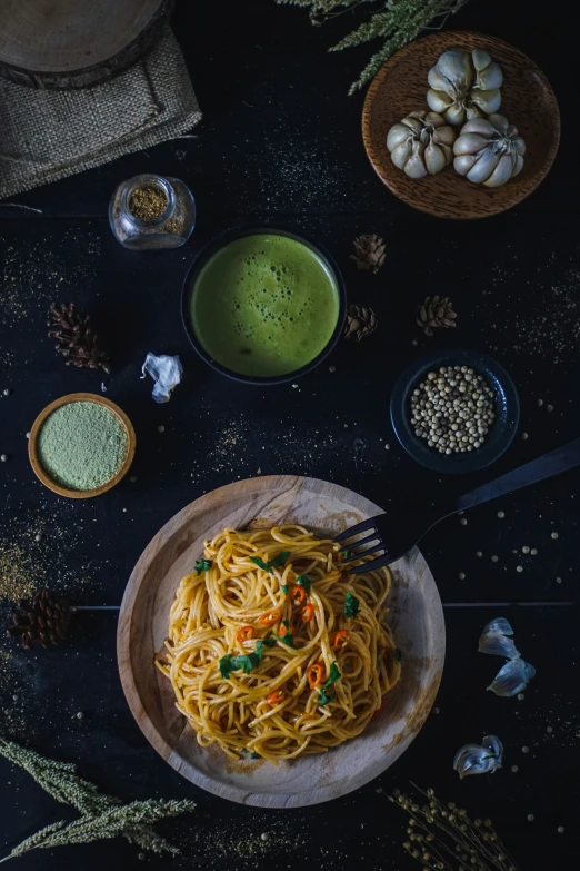 a wooden plate with spaghetti on it and other ingredients surrounding